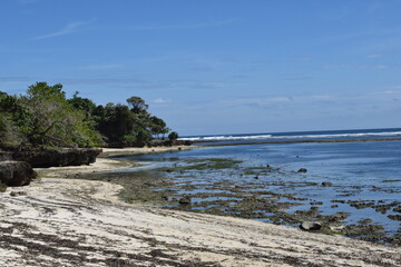 View of a wide beach in Indonesia with a clear blue sky and no people on it. 