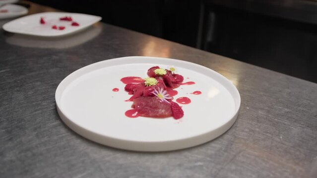 Chef puts edible flowers on tuna carpaccio gourmet dish