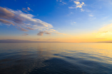 Beautiful cloudy sunset over the sea and mountains. Bright sky in the rays of the orange sun. natural texture