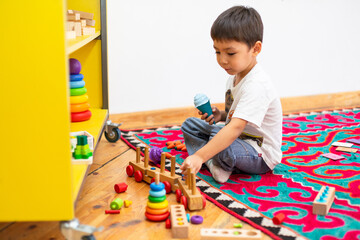 Boy playing with wooden train toy in kindergarten