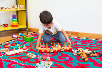 Boy playing with wooden train toy in kindergarten