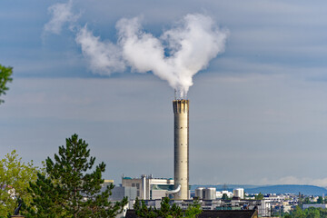 Concrete chimney of waste incineration plant with white smoke on a cloudy summer morning at City of Zürich, Switzerland.