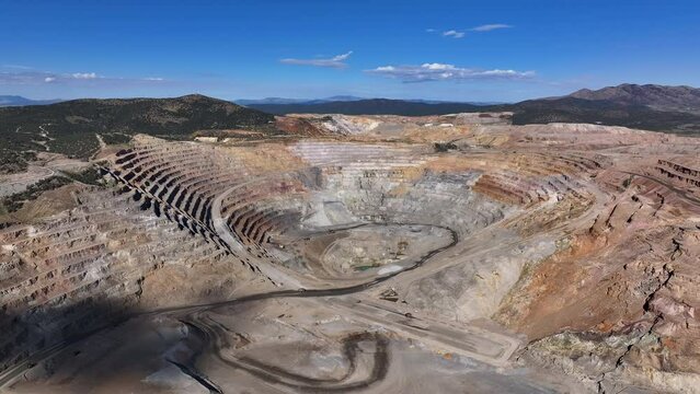 Aerial open pit gold copper mine Ely Nevada slide fast. Boom town along historic Pony Express trail. Rural mining community. Ore transported to Japan for smelting. Precious minerals.