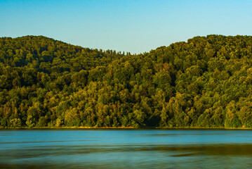 mountains covered with forest by the lake - obrazy, fototapety, plakaty