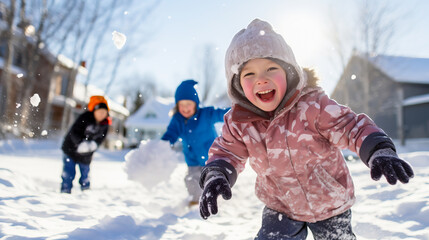 Children playing in the snow during a sunny winters day. Active children, snowball fights and joy in the cold season. Shallow field of view.