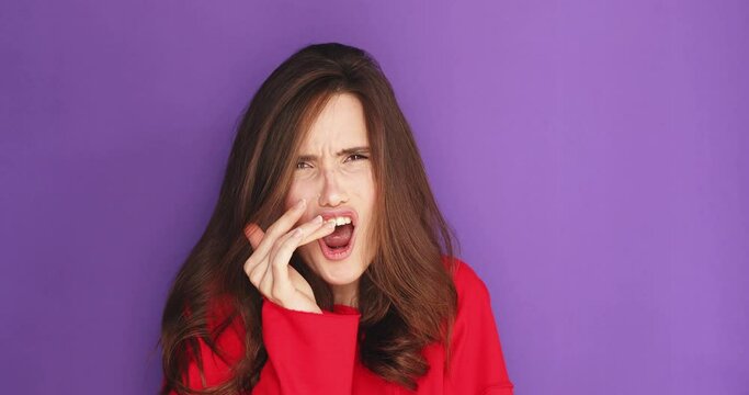 Worried brunette woman watching scary horror movie shock surprise disgust fear from tv series watching online program, watch fighting match or boxing match, woman wear red sweater on purple background
