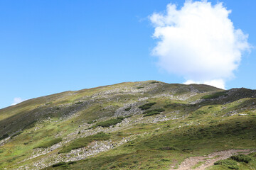 mountain range, grass and stones, blue sky and cloud, shadows from clouds, journey