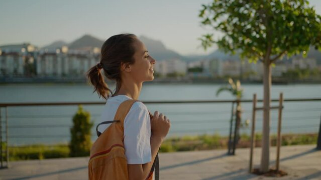 young happy Woman traveler walking bay sidewalk and watching sunset or sunrise with mountains and sea view. Tourism in Turkie, Antalya. active leisure, wanderlust and traveling