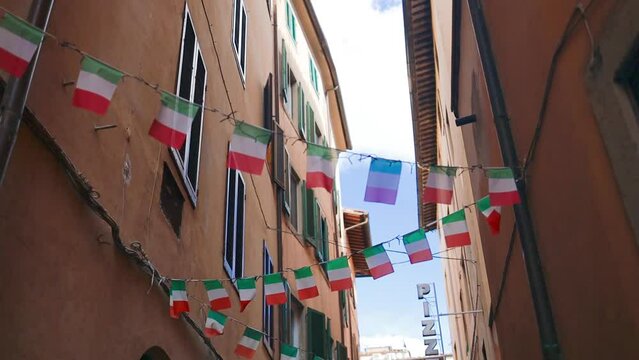 Facade of a yellow building with Italian flags. Holiday in the Italian city of streets with Italian flags and ancient buildings. Pisa, Italy. . High quality FullHD footage