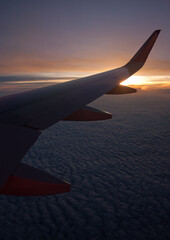 Looking out of window of an airplane into the sunset with clouds