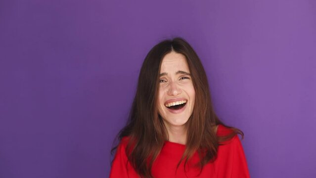 Pretentious brunette woman in red sweater pullover pointing fingers to camera and next laugh on purple background. Girl laughing with a grin, sarcasm, sarcastically.