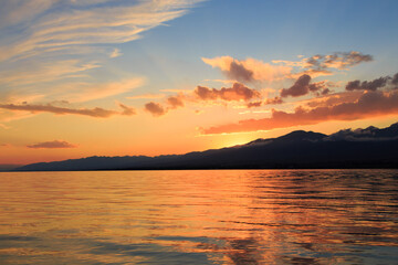 Obraz premium Colorful sunset on the sea. Mountain lake in the rays of the orange sun. Kyrgyzstan, Lake Issyk-Kul.
