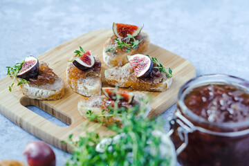 Homemade caramelized onion with figs on bruschetta, fresh thyme served on a wood serving board. Healthy organic food