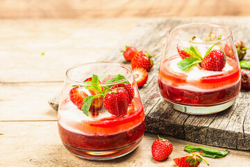 Italian dessert panna cotta in glass with strawberries. Healthy sweet food, hard light, dark shadow