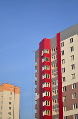 A new multi-colored house against the background of an old high-rise building