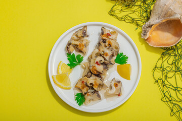 Pickled rapan meat with oil, spices and greens. Healthy seafood rich of omega