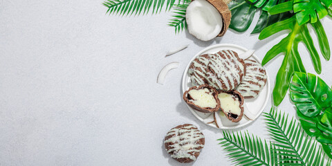 Fototapeta na wymiar Profiteroles choux pastry buns with coconut cream served in tropical style. Palm leaves