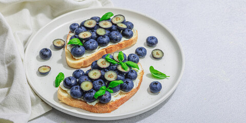 Fresh bread sandwiches with sweet blueberries, cream cheese and basil leaves. Good morning concept