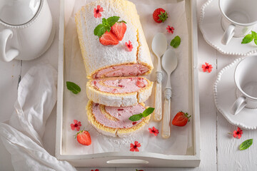 Homemade strawberry roulade with powdered sugar and berry fruits.