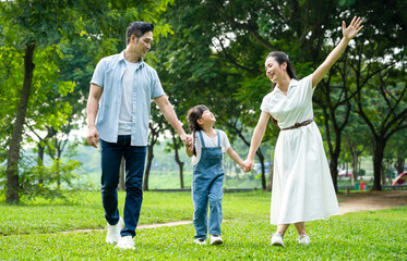 Naklejka na ściany i meble image of asian family walking in the park
