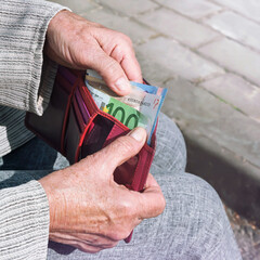 Euro banknotes in the hands of an elderly woman.