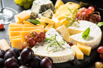 Cheese platter with craft cheese assortment and grape on slate board.