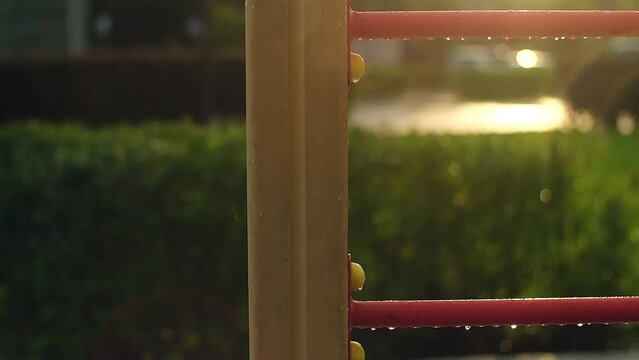 Empty children's playground in the rain. Rain drops falling on swing, wet playground for sports with no people. Summer warm rainy day