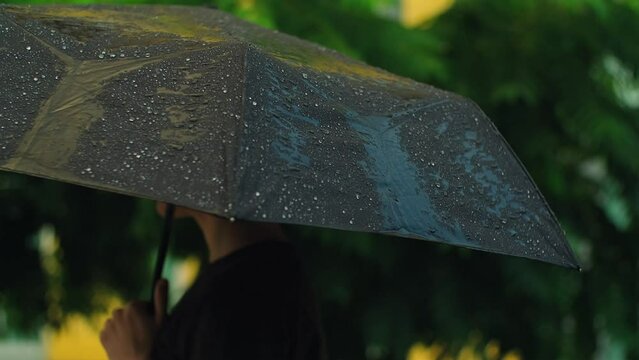 Water rain drops falling on black umbrella. Cloudy rainy season with thundershower, water drops falling on open parasol