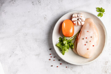 Fresh raw chicken breast with ingredients for cooking.