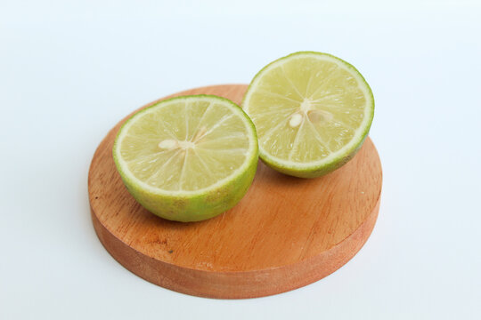 Halves of Green Lime, on wooden base, isolated on white background