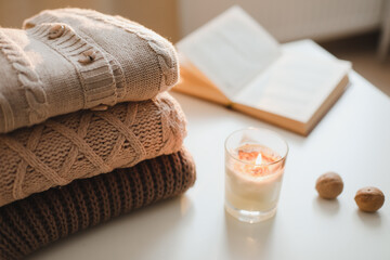 cozy comfortable hygge home atmosphere and still life with a cup, candle, book and sweaters