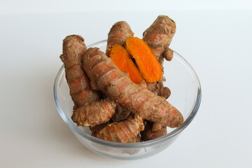 Turmeric or Curcuma longa rhizome in transparent bowl, isolated in white background