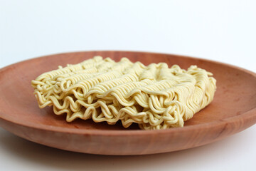 Square instant noodles before cooked, on wooden background, isolated on white background