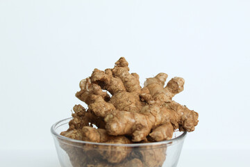 Zingiber officinale rhizome or ground ginger root, inside a transparent bowl. Isolated in white background.