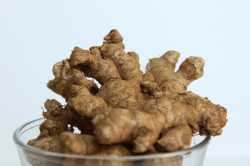 Zingiber officinale rhizome or ground ginger root, inside a transparent bowl. Isolated in white background.