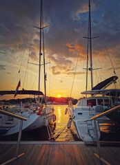 Sunset scene at the harbor as seen through the yachts moored at the pier in the old town of Nessebar, Burgas, Bulgaria