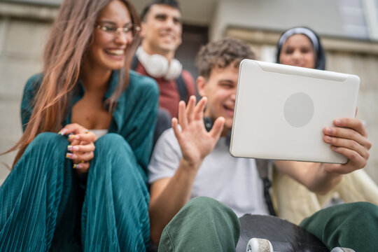 group of students sit in front of school watch video on digital tablet
