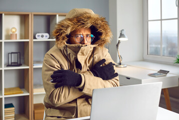 Freezing shivering African American man working in office. Warmly dressed African American man...