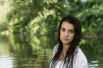 Portrait of a seductive girl posing with wet loose hair outdoors. Horizontally. 