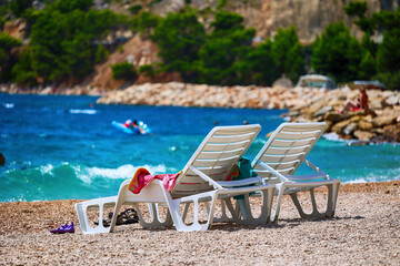 Leżaki na słonecznej plaży nad błękitnym tropikalnym morzem.  - obrazy, fototapety, plakaty
