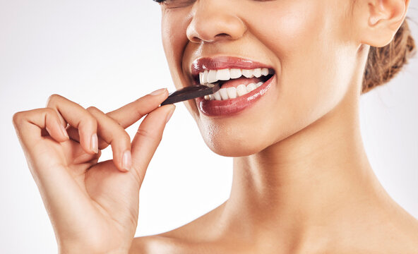Woman, chocolate and mouth for eating, studio and healthy with nutrition, diet and bite by white background. Girl, model and cacao for wellness, detox or cosmetics with detox, teeth or antioxidants