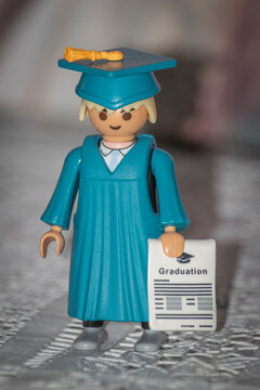 Graduado De Playmobil. Muñeco Con Toga Y Birrete De Color Azul Y Diploma De Graduado.