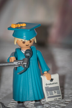 Graduado De Playmobil. Muñeco Con Toga Y Birrete De Color Azul Y Diploma De Graduado.