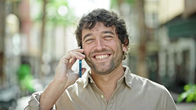 Young hispanic man smiling confident talking on the smartphone at street