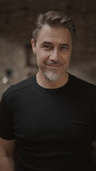 Obraz premium Portrait of smiling middle aged man in a dark room