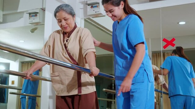 Young physiotherapist assistance elderly patient while guidance therapy with walking in room at hospital or rehab, caregiver or nurse support senior and practicing walking, medical and rehabilitation.