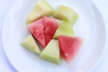 fresh slices of watermelon and melon served on a white plate