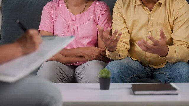 Close up shot of psychologist hands making points on clipboard during couple counselling or therapy session at home - concept of mental illness, consulation and wellness treatment.