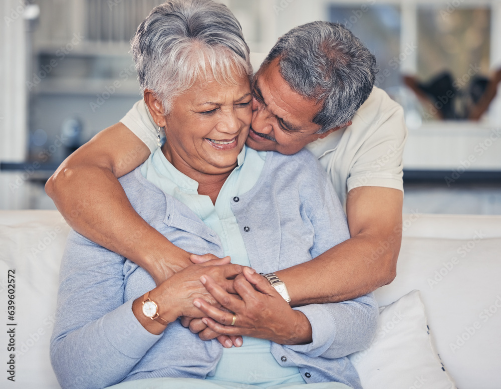 Wall mural Love, hug and a senior couple on a sofa in the living room of their home together during retirement. Support, relax and a elderly man embracing his pensioner wife in a house for relationship bonding