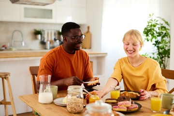 Multiracial couple enjoying breakfast together at home